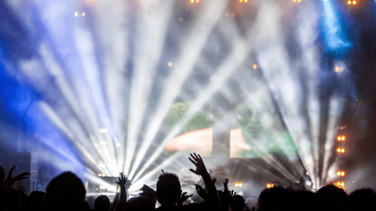 a crowd of people at a concert with their hands in the air