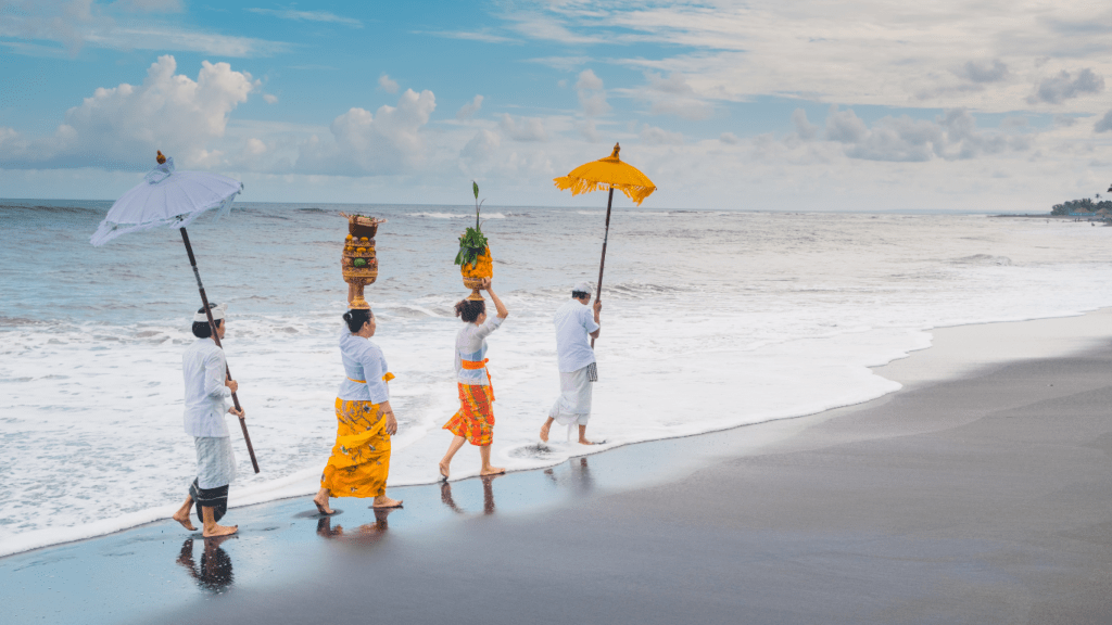 a group of people walking on the beach with umbrellas