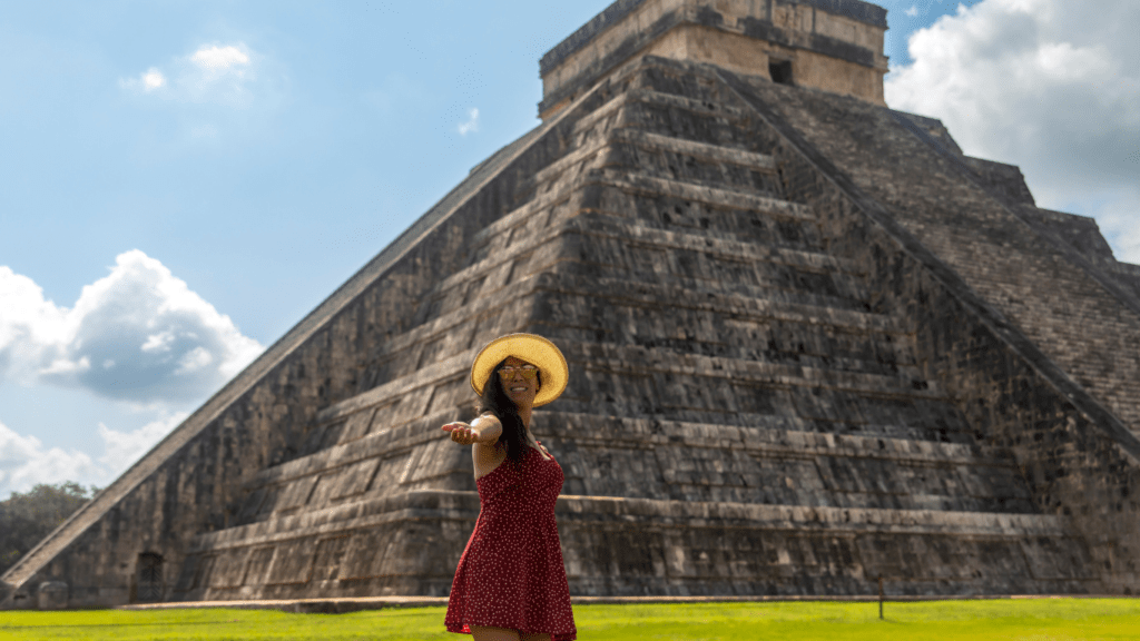 a person in a red dress stands in front of the pyramid at chichen itza