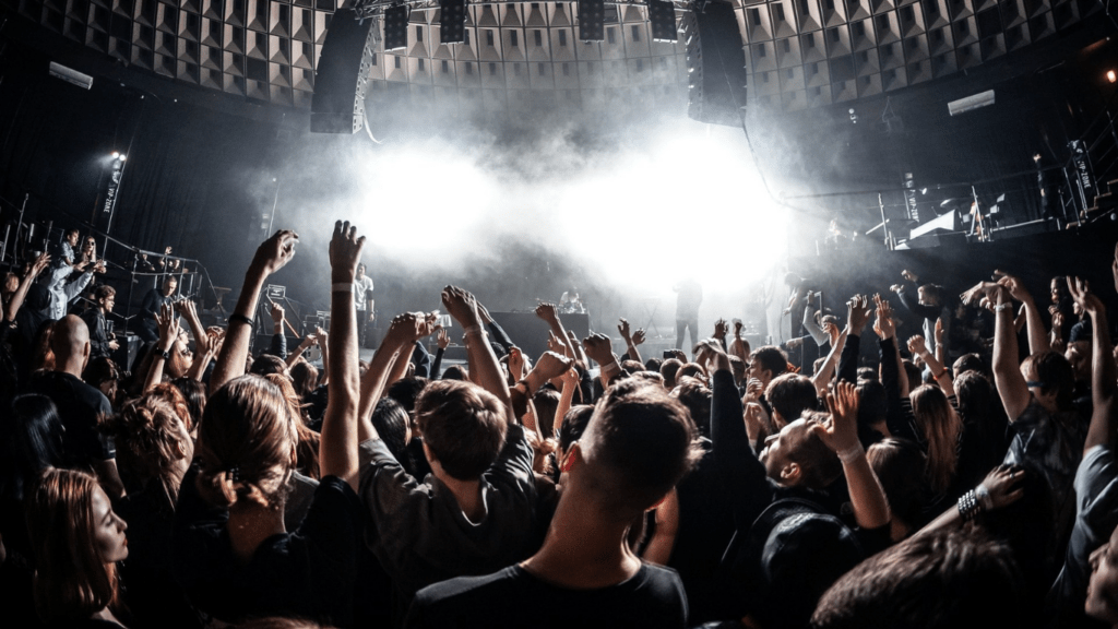 a crowd of people at a concert with their hands in the air