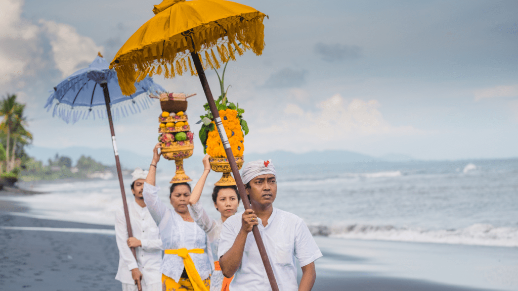 a group of people walking on the beach with umbrellas