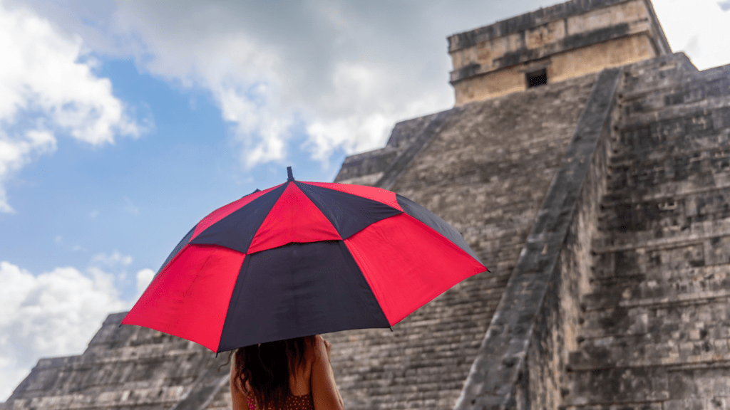 a person in a red dress stands in front of the pyramid at chichen itza