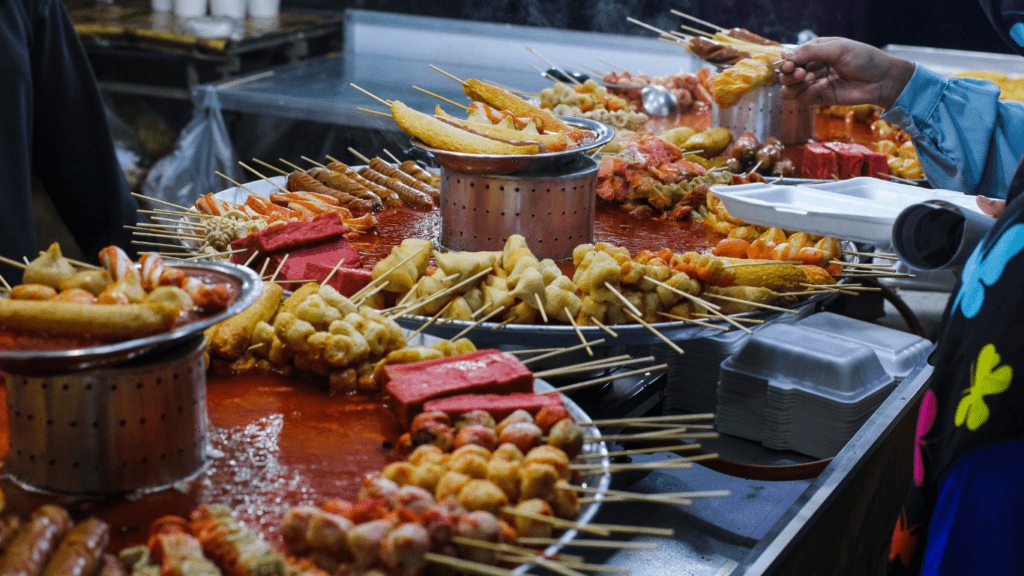 a person is preparing food on skewers at a food stand