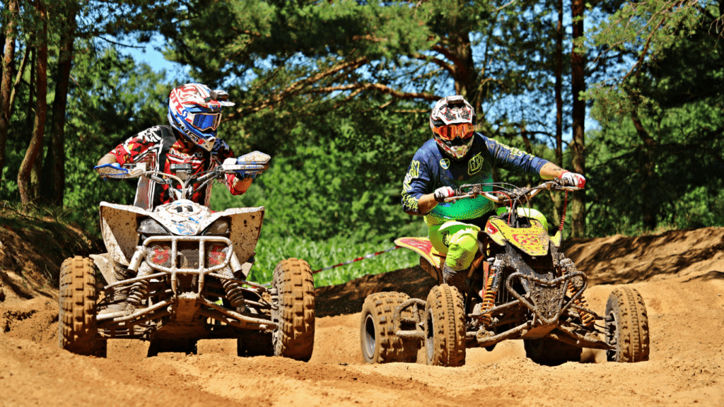 two people riding ATVs on a dirt trail